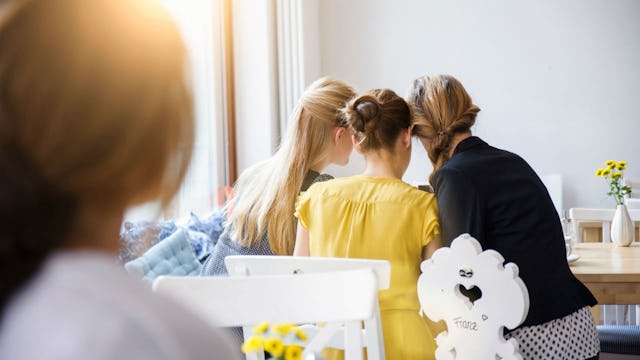 A blurred woman looking at mean women who are talking and have turned their back