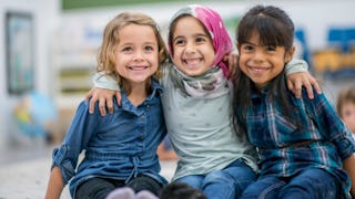 Three female kids sitting and hugging each other and smiling for a photo 