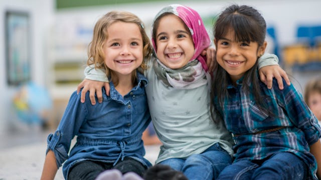 Three female kids sitting and hugging each other and smiling for a photo