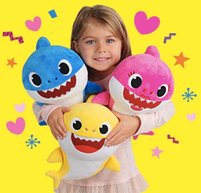 A girl holding singing  "Baby Shark" plushes 