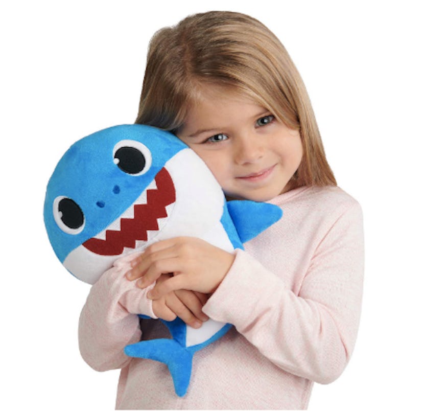  A girl holding a blue singing  "Baby Shark" plush