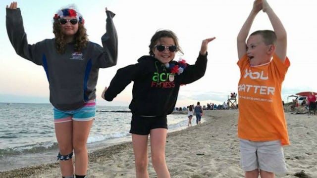 Three kids having fun at the beach, jumping and smiling