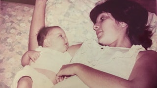 Mother and her only child laying in bed, the baby is lying on the mother's arm.