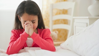 Little girl praying in her bedroom 