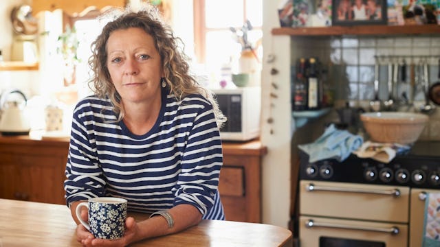 A stay-at-home mother posing with a coffee cup in her kitchen