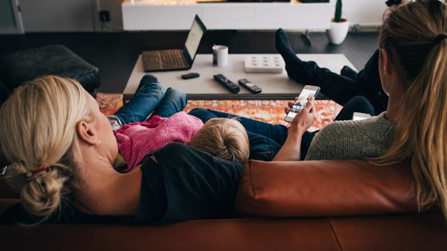 A mother using her phone while hugging her son on the couch thinking about having another baby
