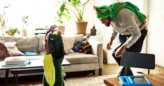 Father and son dressed as dragons playing in living room