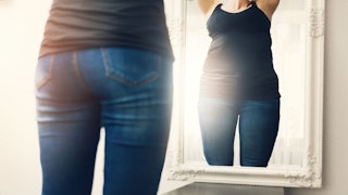 woman looking in the mirror suffering from an eating disorder