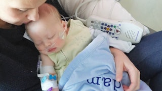 A mother holding a baby diagnosed with RSV, having a breathing tube and monitor in a hospital bed