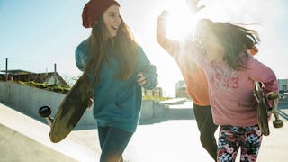 Competitive teenage girls at the skate park carrying skateboards