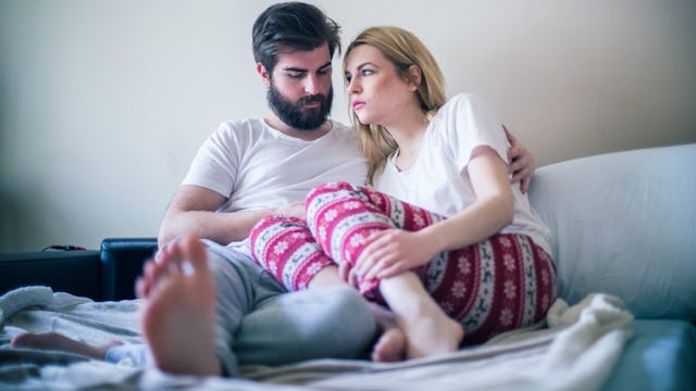 A couple struggling with secondary infertility comforting each other while sitting on the bed