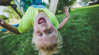 A blond kid with ADHD on a swing upside down 