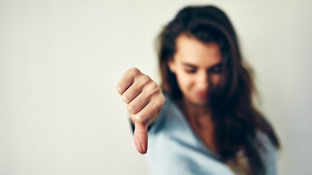 A girl with long hair pointing her thumb down