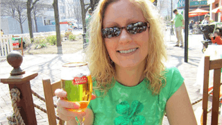 A blonde woman smiling with a beer in her hand following a near-death experience.