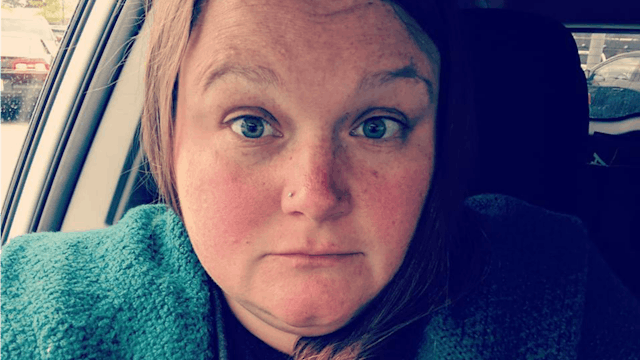 Selfie of a woman with brown hair, her eyes are wide open and eyebrows risen while she is sitting in...