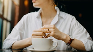 A woman sitting with a coffee cup in front of her 