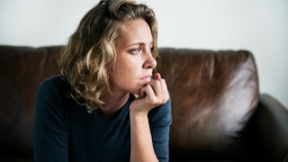 A woman sitting down on the couch looking away in fear of getting divorced