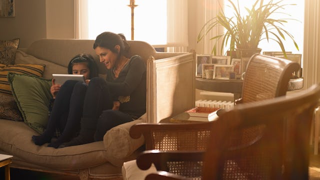 A mother who might cancel plans having fun on a tablet with her daughter