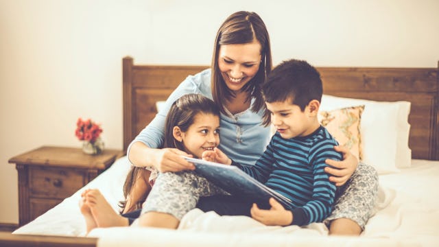 A mother reading a book with her two kids in bed to reduce their Sunday night anxiety