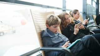 Mother and two children sitting on chairs and holding their phones