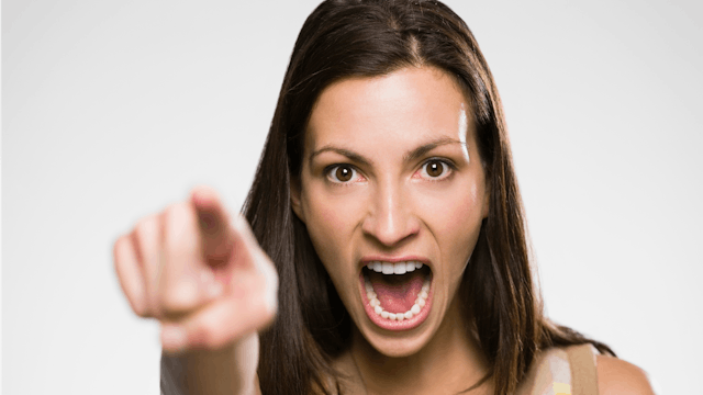 Angry brown haired woman pointing her finger in the front with her mouth wide open