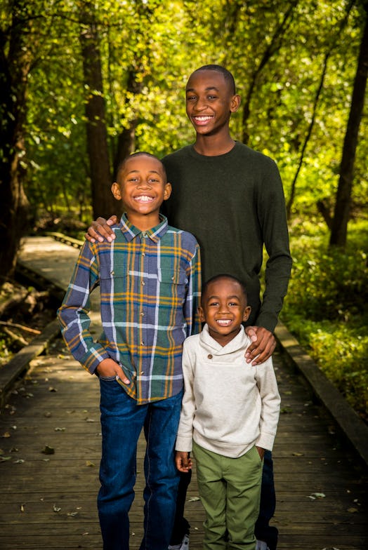Three black sons smiling in the forest while posing for the picture