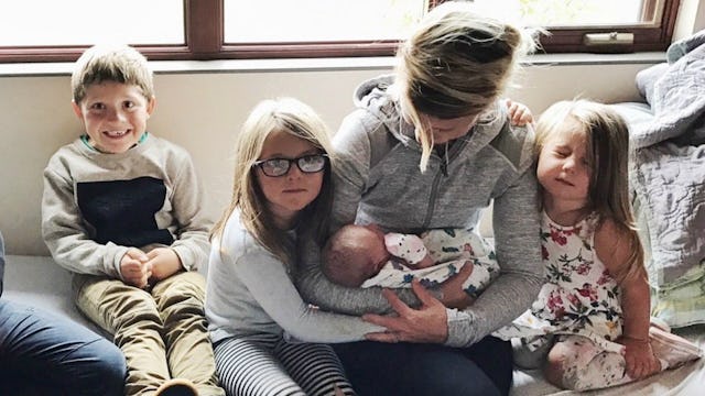 A young woman sitting down on a couch with her and her friend's kids
