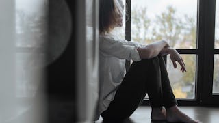 Abused young woman sitting on a floor feeling depressed