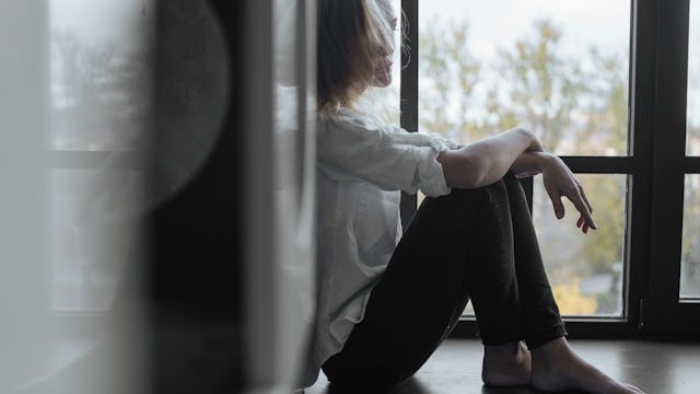Abused young woman sitting on a floor feeling depressed
