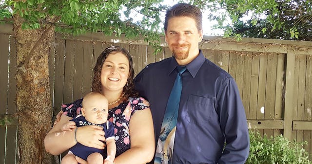 Megan Hansen holding her baby, smiling and posing next to her husband in a backyard