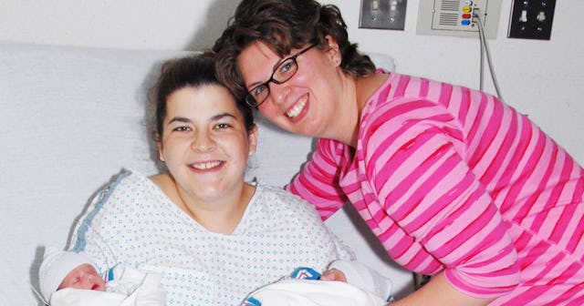 A woman posing with her surrogate and her newborn twin girls in a hospital room