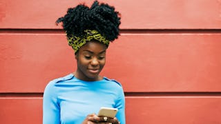 A woman typing on her phone, happy because she can troll her ex on social media