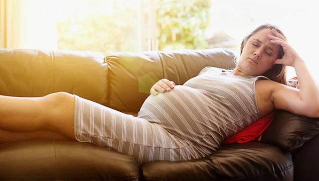 A pregnant woman laying on a couch in the summer while it's hot outside which could induce early lab...