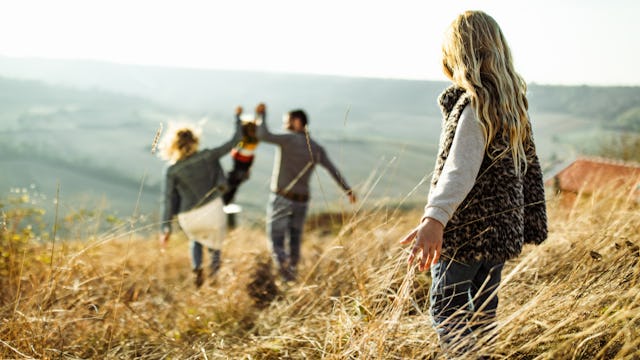 A Girl Watching A Man And A Woman Lifting Up A Kid In The Distance