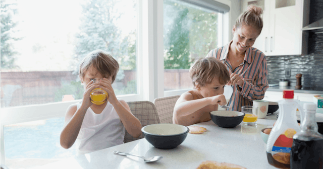 A mom with her two stepsons sitting at a table eating breakfast