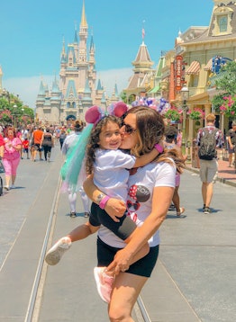 Michelle Dempsey holding and kissing her daughter with plush pink ears in Disney World
