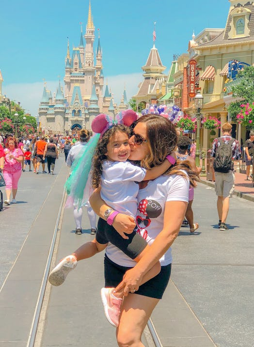 Michelle Dempsey holding and kissing her daughter with plush pink ears in Disney World