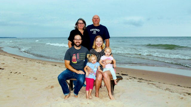 Megan Moore with her husband, her parents, and her children smiling and posing at a beach