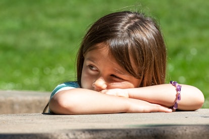 A girl looking into the distance with her head placed on her arms 