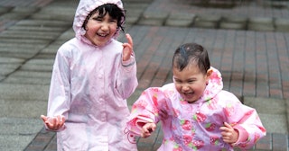 Two girls in pink raincoats playing in the rain and smiling