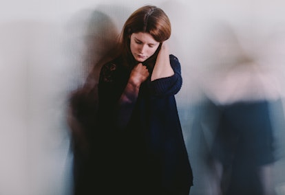 An anxious girl standing alone and looking down with a blurred background