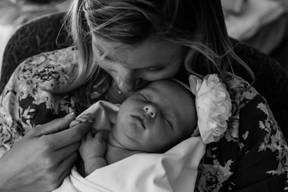 Black and white image of a mother in a floral shirt holding her newborn baby