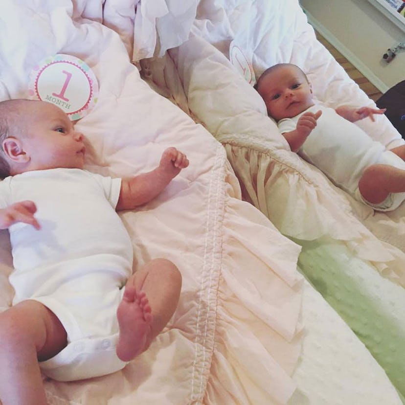 A one-month-old baby lying and looking at itself in the mirror