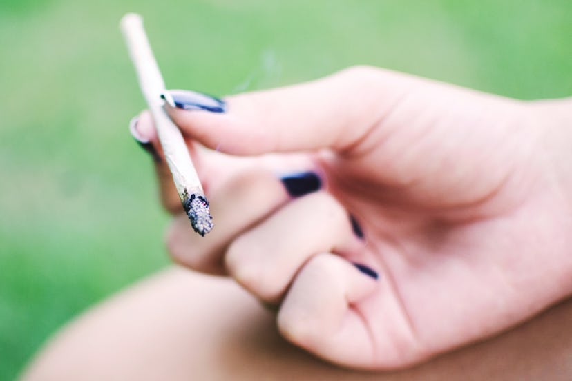 Woman's hand holding a lit joint.