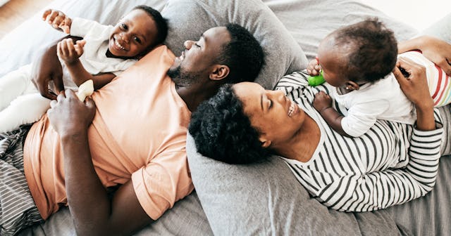 Happy parents lying on a couch with their two kids