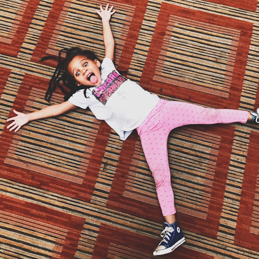 Young girl, that doesn't 'act right,' having fun while lying down on a carpet