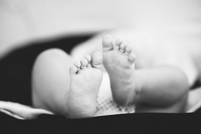 A baby lying on its back with its feet up in black and white
