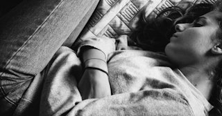 Black and white photo of a girl who has PANDAS curled up on a bed with crossed arms on her stomach
