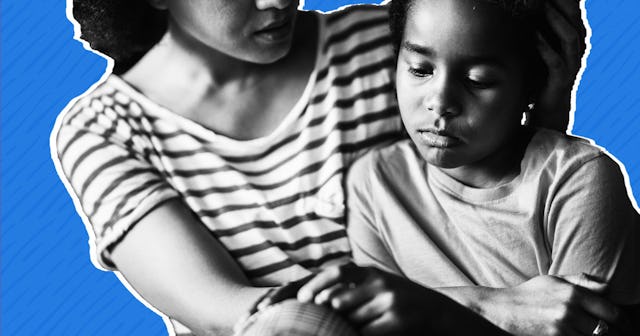 Black and white image of mom hugging her sad daughter that’s sitting next to her with a blue backgro...