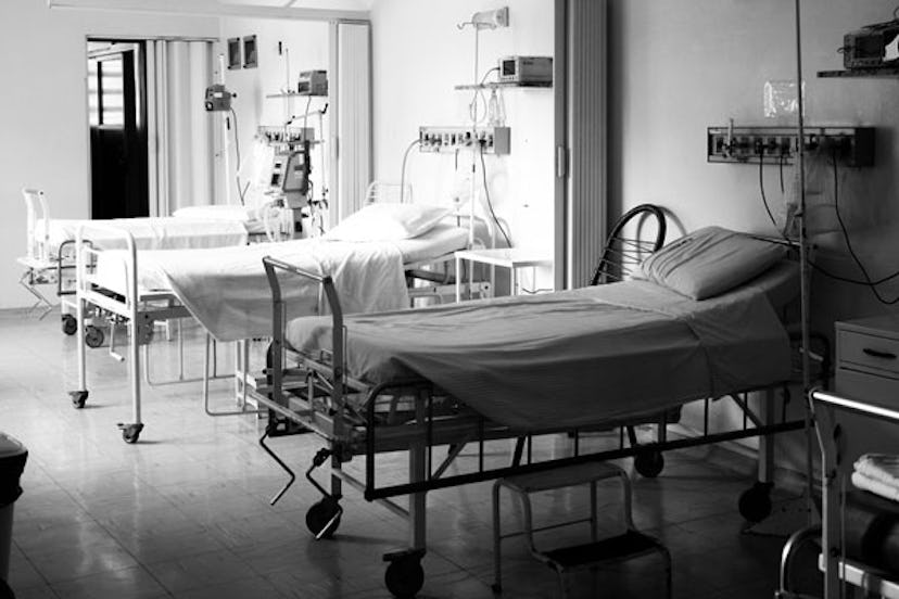 Black and white photo of three hospital beds with IV stands